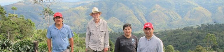 Kaffeebauern aus einer Kooperative in Peru stehen gemeinsam vor einer Berglandschaft.