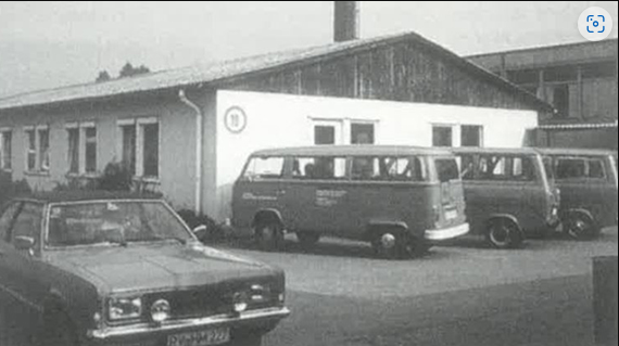 Historisches Foto des ursprünglichen Gebäudes von Cafesito, in dem die Kaffee Behindertenwerkstatt ihren Anfang nahm. Bild mit alten Autos vor dem Haus und dem Charme vergangener Tage.