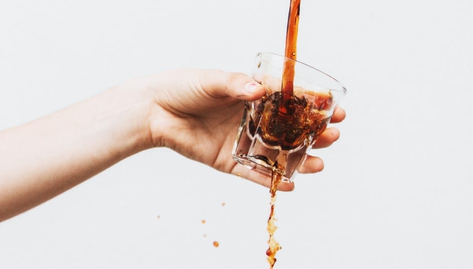 Eine Hand hält ein Glas, in das frisch gebrühter Cafesito-Kaffee gegossen wird. Ein Moment echter Handwerkskunst und Kaffeegenuss.